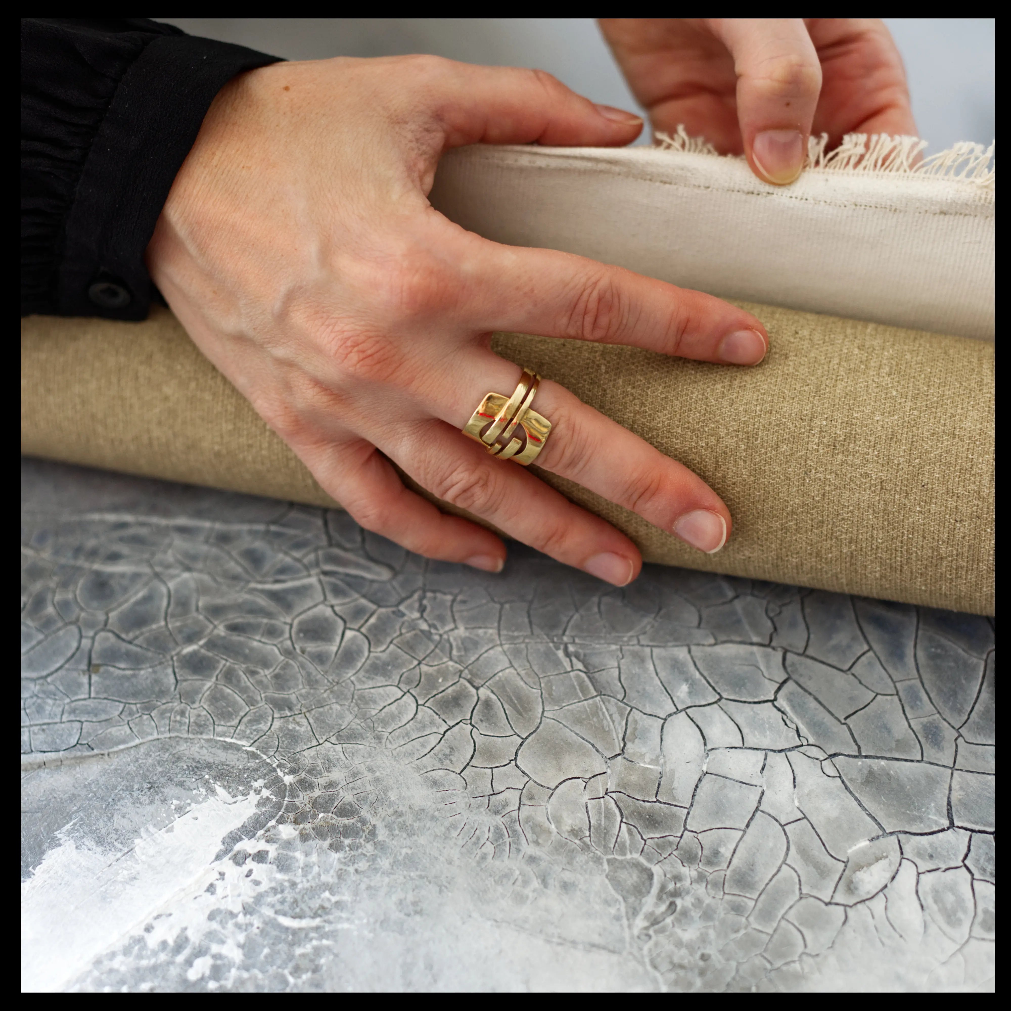 Close up on a textured canvas painting and the painters hands working on the canvas in the art studio.